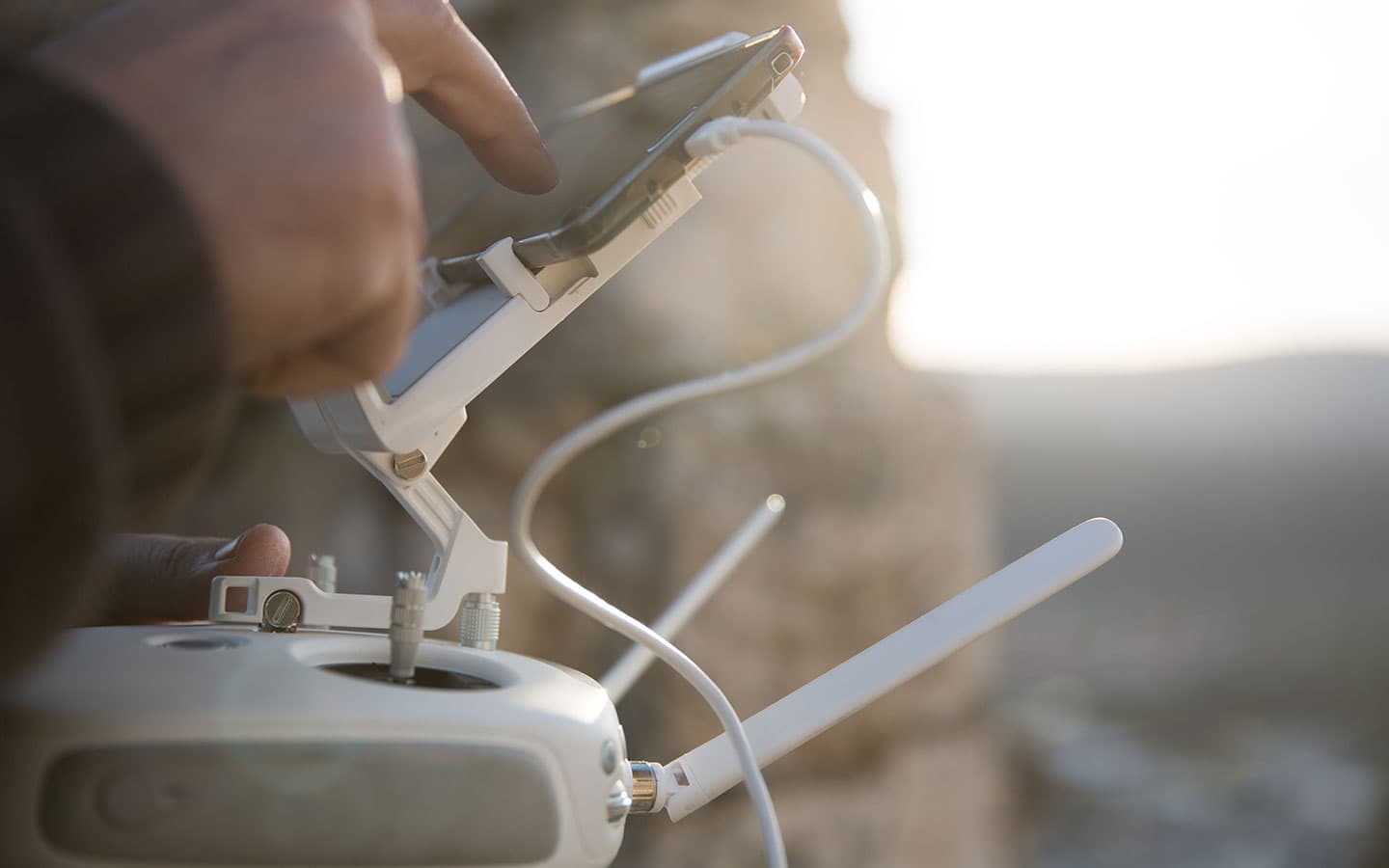 Controlador de drone nas mãos com pôr do sol dourado ao fundo